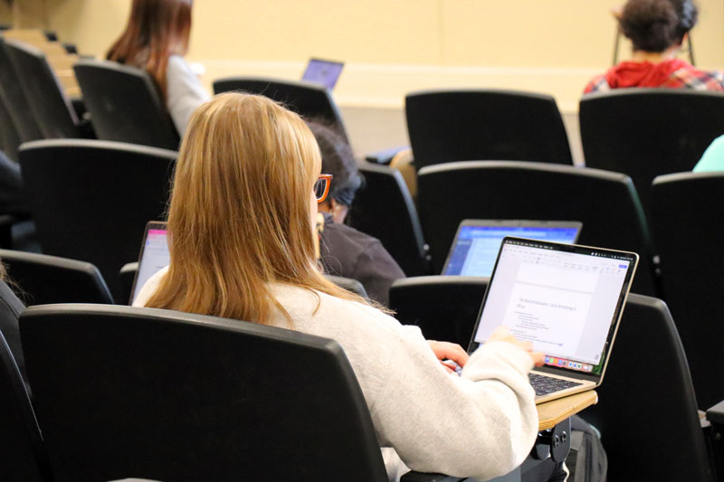 student sitting in a lecture hall with laptop